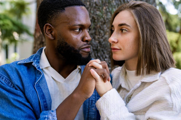 istock Young multiethnic couple holding hands and looking at each other 2194757545