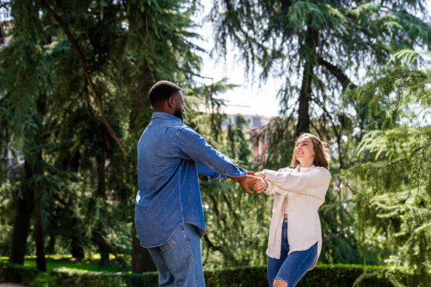 istock Multiethnic couple holding hands and spinning in the park 2194757603
