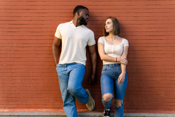 istock Multiethnic couple leaning against a red brick wall 2194757635