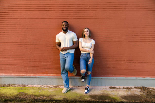 istock Multiethnic couple leaning against a red brick wall 2194757653