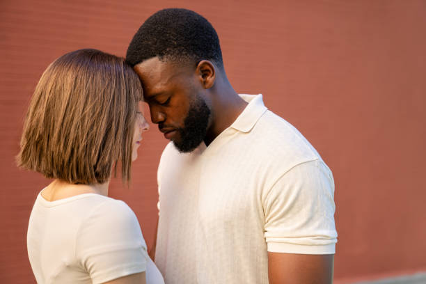 Multiethnic couple touching foreheads with closed eyes and serious expression