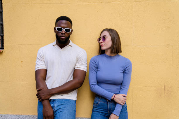 istock Multiethnic couple leaning against yellow wall wearing sunglasses 2194757928