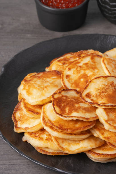 istock Delicious stack of golden pancakes served with cream and caviar on a rustic table 2194759023