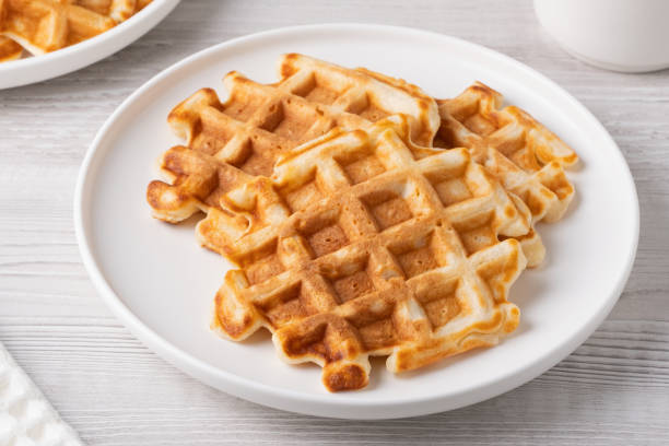 istock Crispy golden waffles served on a round white plate in a cozy kitchen setting 2194759030