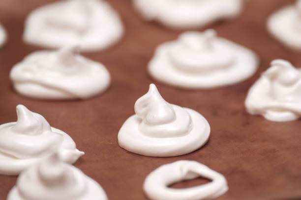 istock Delicate meringue peaks rest baking tray, ready baking. These fluffy white confections made from whipped egg whites and sugar perfect for desserts 2194765637