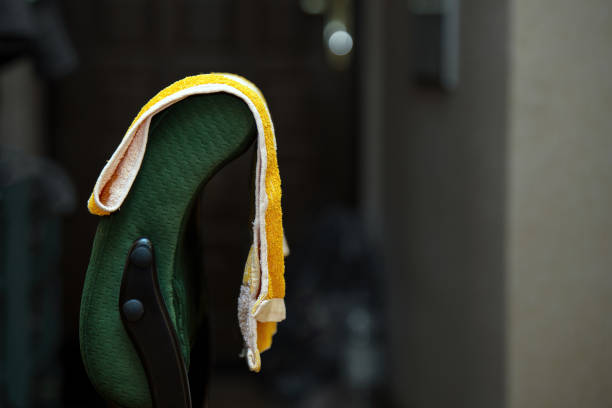 cozy green upholstered chair featuring a bright yellow terry towel hanging from its back. Perfect for interior design, home decor, or relaxation themes