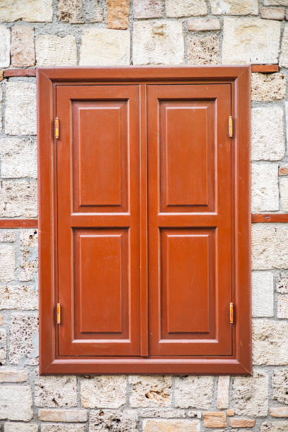 Closed wooden window on stone wall with rustic charm.