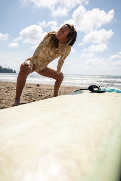 istock Woman Stretching on Beach Next to Surfboard 2194771691