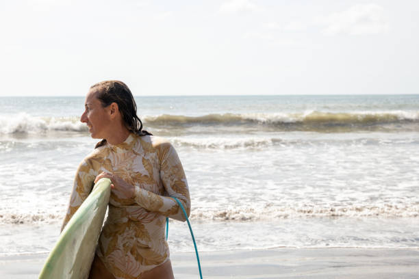 istock Woman Holding Surfboard on Sunny Beach 2194771903