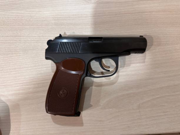 istock Black and brown gun is on a wooden table 2194771977