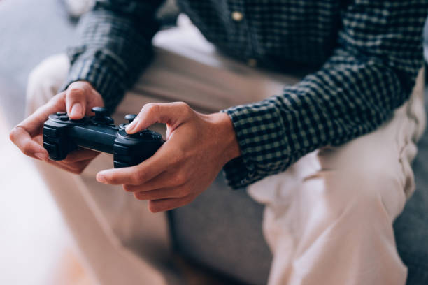 A detailed view showcasing hands gripping a gaming controller, emphasizing engagement in electronic entertainment while seated indoors.
