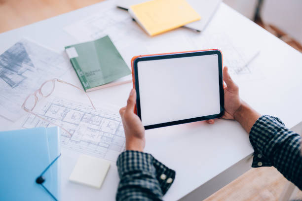 istock Hands Using a Blank Tablet on a Desk with Blueprints and Glasses 2194772924