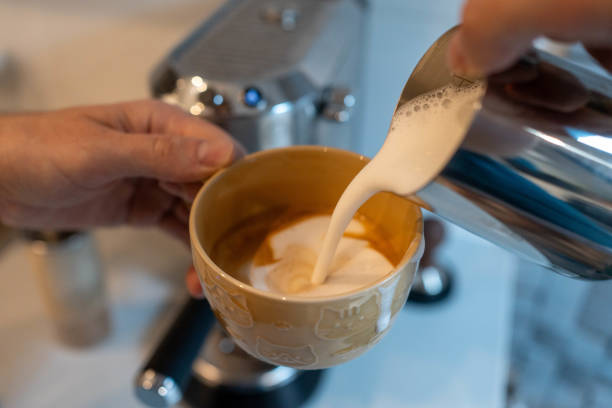 Man Adds whipped milk to espresso.