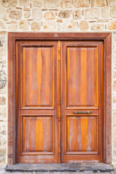 Rustic wooden door with metal handle on stone brick wall.