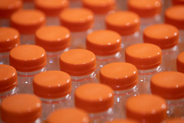 Workers organize plastic bottles with orange caps in a recycling facility, emphasizing the importance of sorting waste.