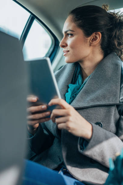 istock Woman using digital tablet on the back seat of a car 2194793001