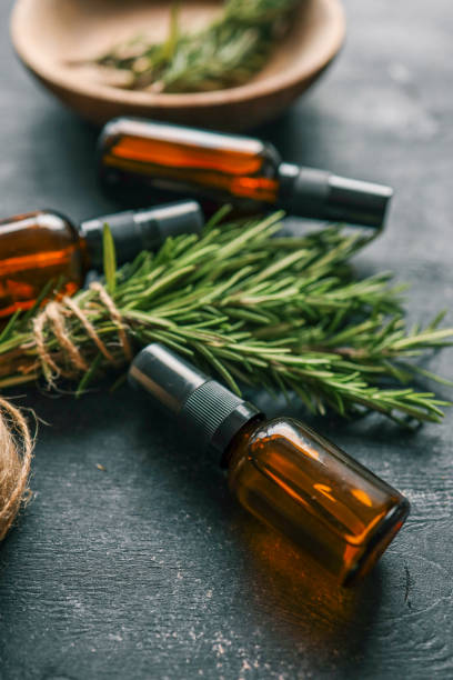 istock Amber glass spray bottle with a black cap placed on a dark rustic surface, surrounded by rosemary sprigs and natural decor elements. Concept of natural, eco-friendly cosmetics or aromatherapy products 2194793475