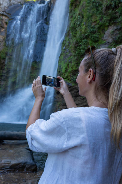 istock Woman Photographing Scenic Waterfall 2194797357