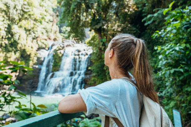 istock Woman Admiring Waterfall from Jungle Bridge 2194797615
