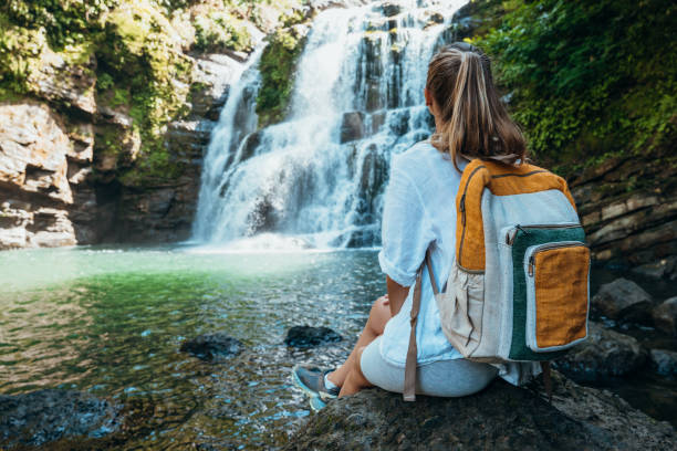 istock Young woman with backpack enjoying waterfall view in nature 2194797685