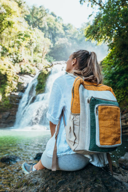 istock Young woman with backpack enjoying waterfall view in nature 2194797686