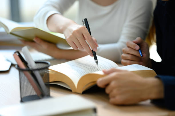 istock Close up of university students collaborating on studying material in library 2194806438