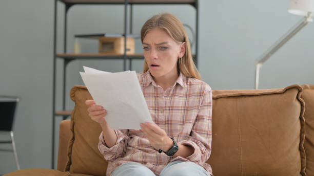 istock Upset Young Woman Shocked while Reading Documents at home 2194811515