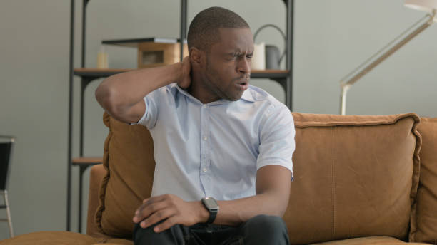 istock African Man with Neck Pain Sitting on Sofa at Home 2194813532