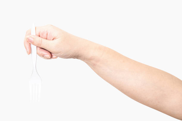 Female hand holding a white plastic fork isolated on white background with clipping path.