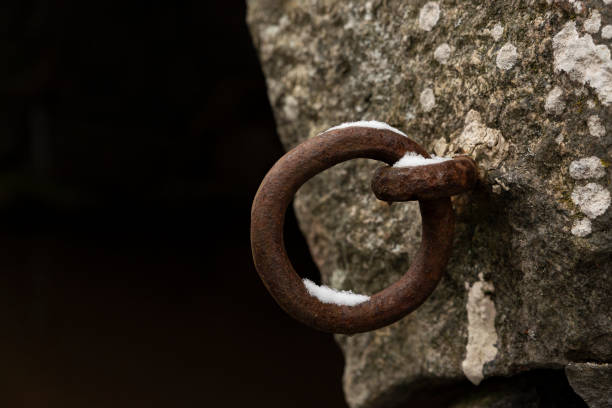 Old rusty iron ring on the stone of the bridge on a winter day