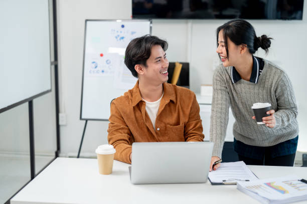 istock Two positive Asian businesspeople brainstorm and discuss a project together in a modern office. 2194815421
