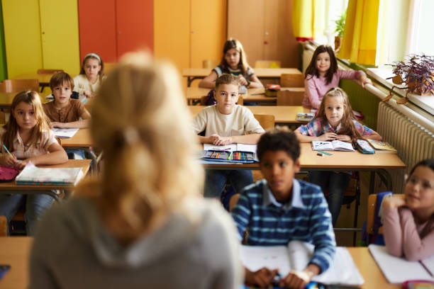 istock Elementary students listening to their teacher on a class at school. 2194816342