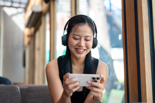 istock A cheerful Asian woman enjoys playing a mobile game while relaxing in a cafe. 2194820881