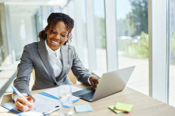istock Happy black businesswoman taking notes while working on laptop in the office. 2194824000
