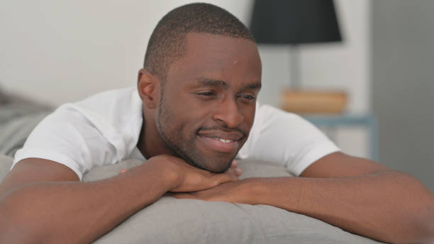 istock Pensive African Man Lying on Stomach in Bed 2194824513
