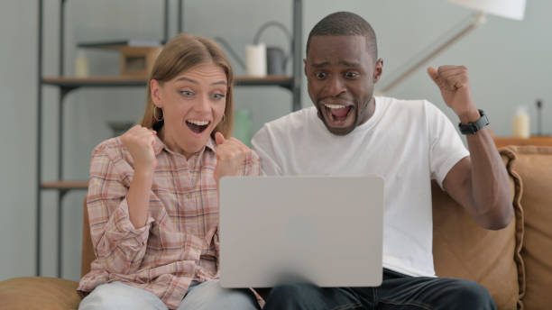 istock Interracial Couple Celebrating Work on Laptop at Home 2194826071