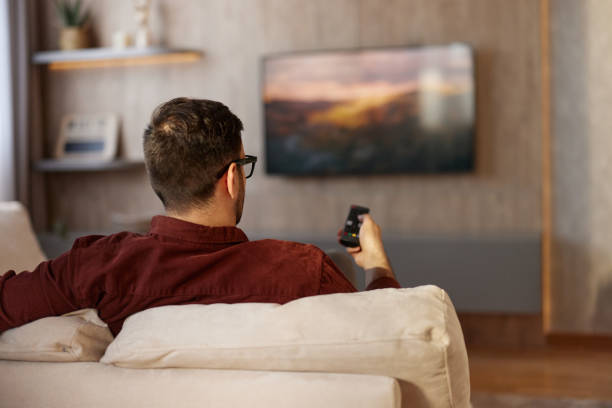 istock Back view of a man watching TV at home. 2194826147