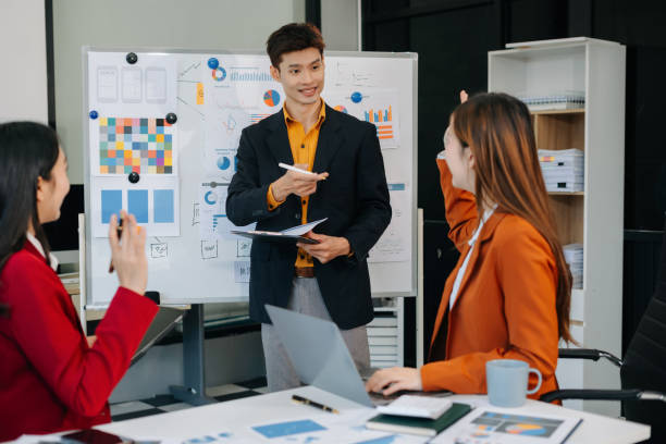 istock Group of professionals participating in meeting or workshop. presenter standing near flip chart give presentation interact with participants, attendee ask questions, share opinion or solutions. 2194826294