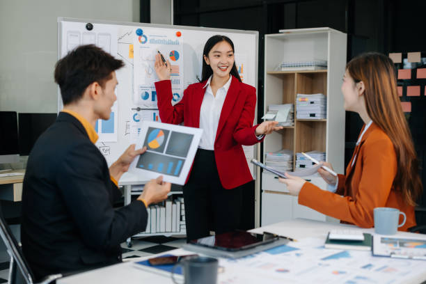 istock Group of professionals participating in meeting or workshop. presenter standing near flip chart give presentation interact with participants, attendee ask questions, share opinion or solutions. 2194826310