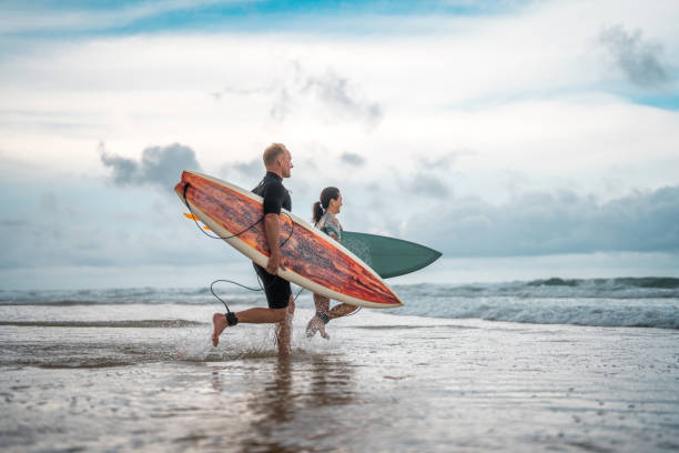 istock Energetic Diverse Surfing Couple Running on Gold Coast Beach 2194826650