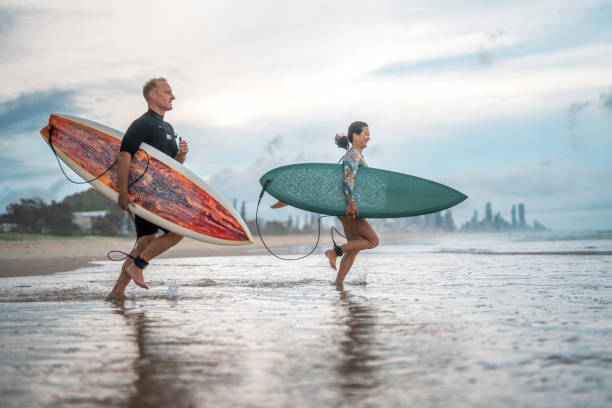 istock Excited Surfing Couple Running on Gold Coast Beach 2194826652