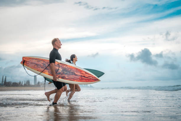 istock Diverse Surfing Couple Joyfully Running into Ocean Waves 2194826656