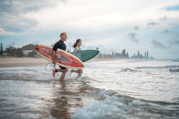 istock Joyful Mixed-Race Surfing Couple Running into Waves with Surfboards 2194826661
