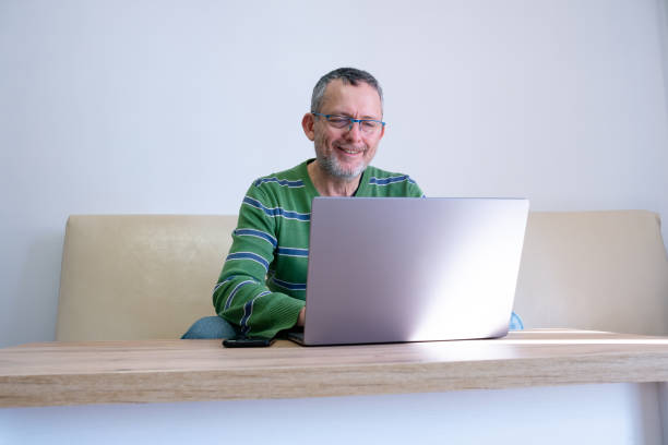 istock Cheerful mature man works on a laptop at home. 2194829454