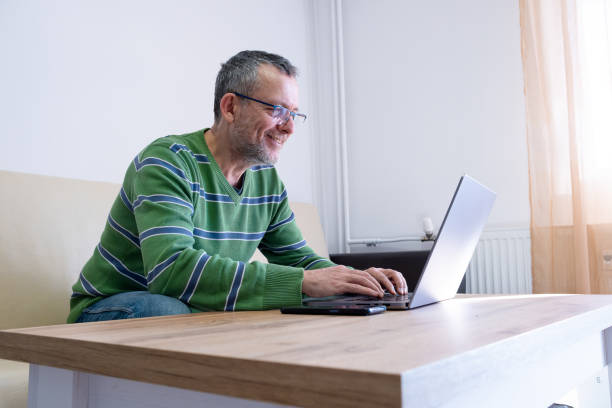istock Cheerful mature man works on a laptop at home. 2194829495
