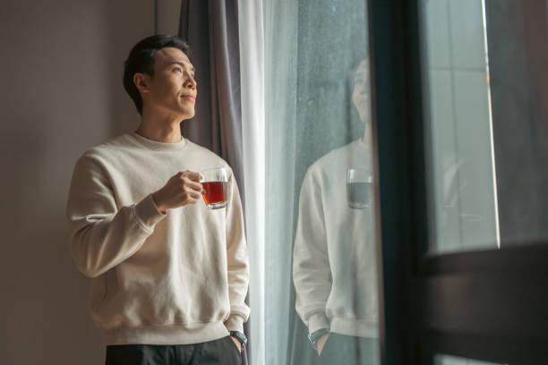 istock Young Asian Chinese man having cup of coffee while standing at home. 2194829879