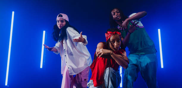 Group of hip hop dancer dancing together in a moody studio with tube neon lights.