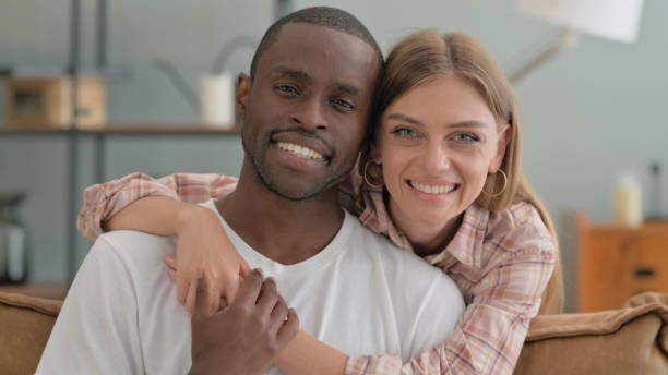 istock Smiling Interracial Couple Hugging and Looking at Camera 2194832380