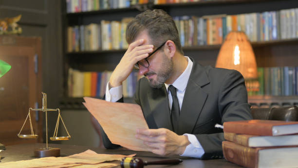 Tense Middle Aged Lawyer Shocked while Reading Court Orders in Office Tense Middle Aged Lawyer Shocked while Reading Court Orders in Office Wrongful Death Attorney stock pictures, royalty-free photos & images