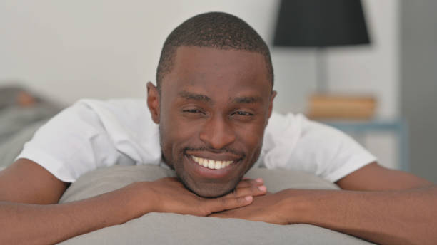 Close up of Smiling African Man Looking at Camera in Bed